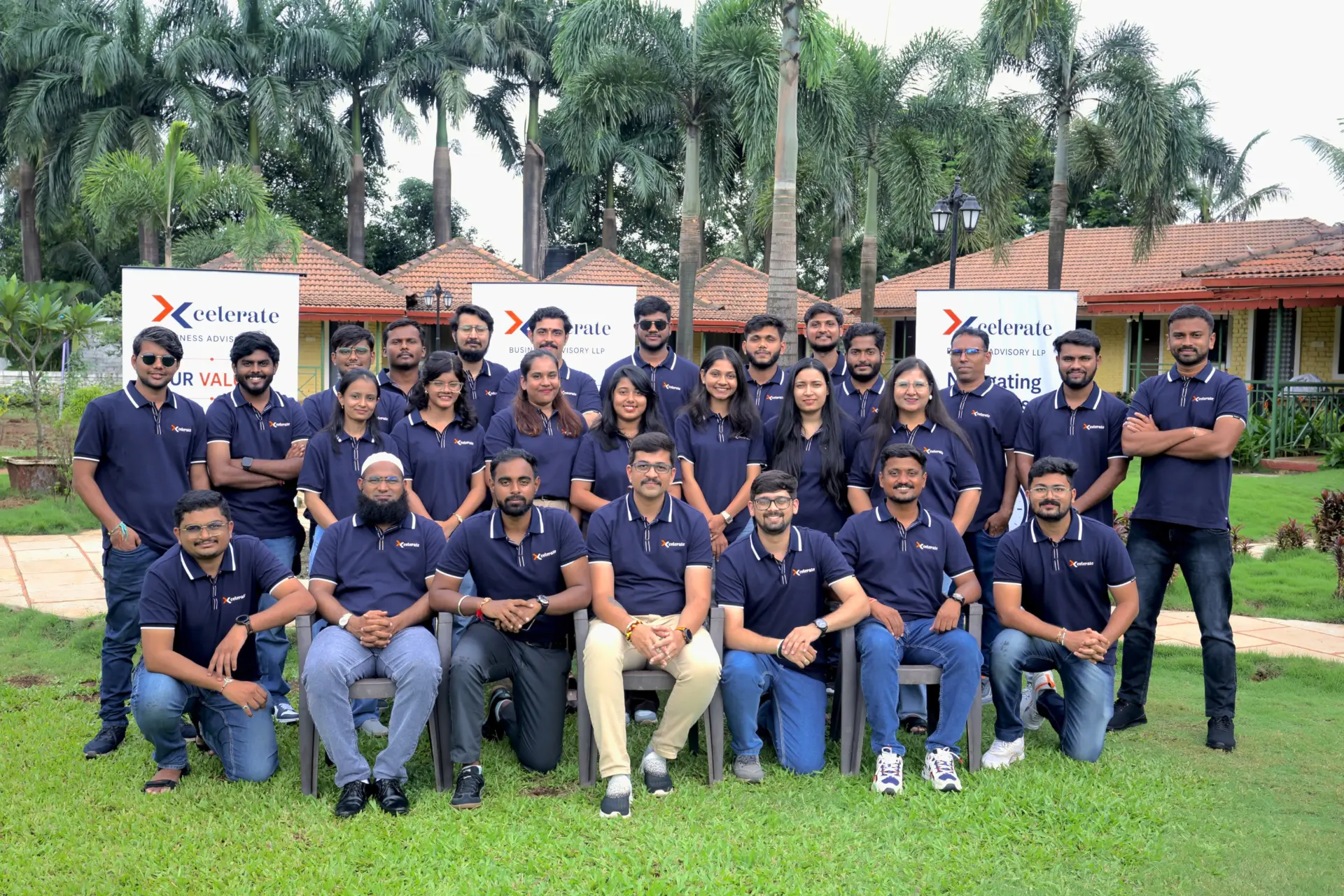 The Xcelerate Advisory team gathered on a lawn in front of Xcelerate banners