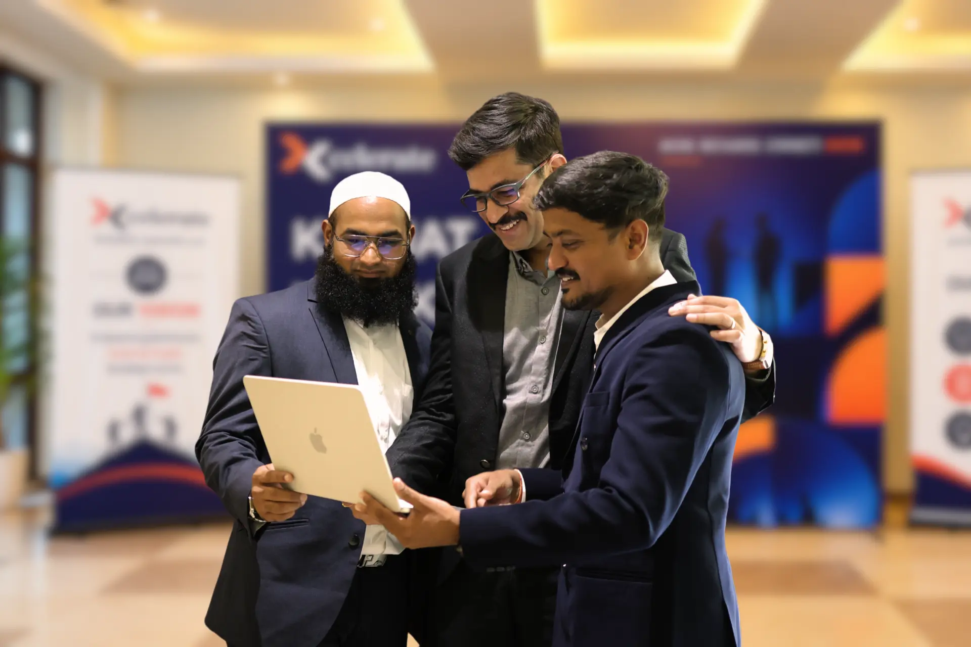 Three Xcelerate Advisory members reviewing a laptop together at an event